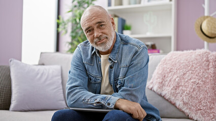 Mature bearded man in casual clothing relaxing in a modern living room, portraying a relaxed lifestyle at home.