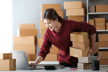 Startup SME small business entrepreneur of freelance Asian woman wearing apron using laptop and box...