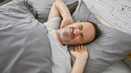 Exhausted, middle age man with grey hair, comfortably resting in the cozy comfort of his bedroom,...