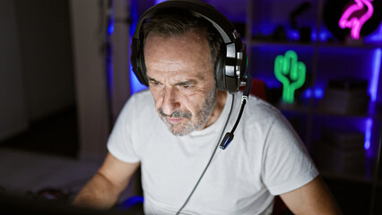 Middle-aged grey-haired man engrossed in intense gaming session on his stream, immersed in the neon...