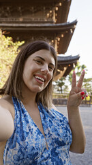Fototapeta premium Confident latina beauty, enjoying a casual, fun selfie moment at kyoto's to-ji temple. peace sign high for the snap, capturing her radiant smile and positivity.