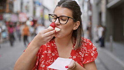 Gorgeous hispanic girl in specs relishing strawberry japanese mochi on osaka's famous dotonbori...