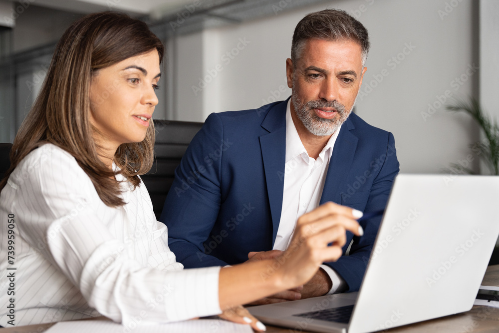 Wall mural team of diverse partners sitting at table mature latin business man and european business woman disc