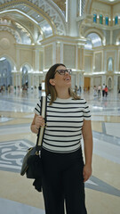 Obraz premium A happy young woman admiring the grand architecture of qasr al watan palace in abu dhabi, uae.