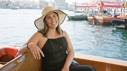 Smiling woman enjoying a traditional boat ride on dubai creek with the old city backdrop.