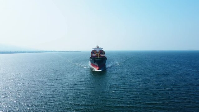 Aerial view in front of cargo ship carrying intermodal cargo containers in sea, concept intermodal logistic service