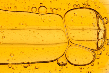 Golden yellow abstract oil bubbles or face serum background. Oil bubbles macro photography.