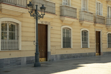 Charming street in the city of Cádiz (Andalusia, Spain). Historical facade with pastel yellow...