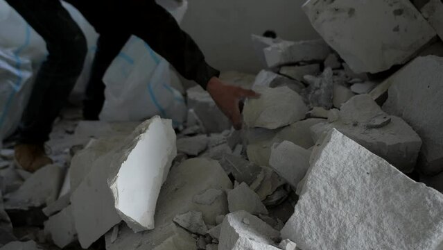 A man fills a garbage bag with fragments of a destroyed wall. Cleaning after dismantling