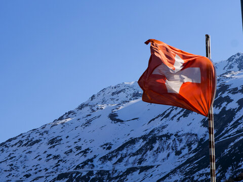 Windy Swiss Flag in front of Swiss Alps Mountain.