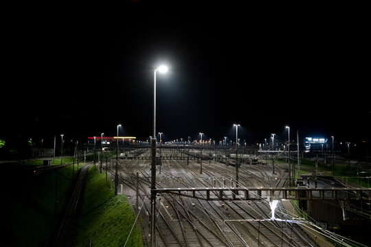 Freight station at night in Zurich, Spreitenbach. Freight trains are illuminated by bright headlights. In the background is a light layer of fog.