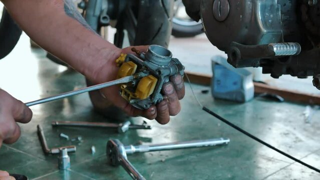 Motorcycle mechanic's hands stained with engine oil are using a screwdriver to repair a motorcycle.4k video
