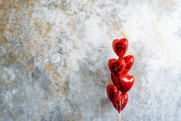 A cluster of red heartshaped balloons against a gray backdrop