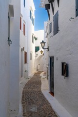 narrow alley leading through a maze of whitewashed buildings in the village center of Binibeca Vell