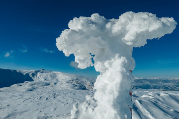 Frozen fence forming sculptures on snow covered alpine meadow with scenic view of landscape of Kor Alps, Lavanttal Alps, Carinthia Styria, Austria. Winter wonderland Austrian Alps. Tranquil atmosphere