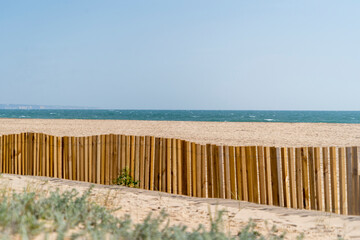 Sand beach with ocean behind, dune wood fence and sea grass