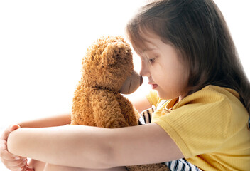 Caucasian child girl hugs teddy bear toy, Little kid portrait on white background, friendship and relationship concept. Feelings and emotions.
