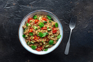 Quinoa tabbouleh salad in a bowl, a healthy dinner with tomatoes and mint, overhead flat lay shot with a fork - 739967484