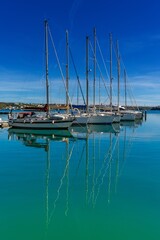 vertical view of moored sailboats in the harbour of Mahon on Menorca with reflections in the turquoise water