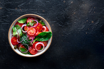 Salad with tomato, fresh leaves, and onions, overhead flat lay shot. Healthy diet, simple vegan recipe, with copy space - 739968856