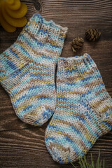 Title: Colorful hand knitted kids socks and dried orange slices on dark wooden background