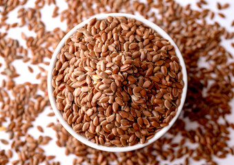 Organic Whole Brown Flax Seeds in a White Ceramic Bowl. Top View.