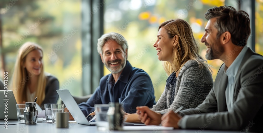 Poster group of professionals smiling and talking in a bright modern office with a view of the trees outsid