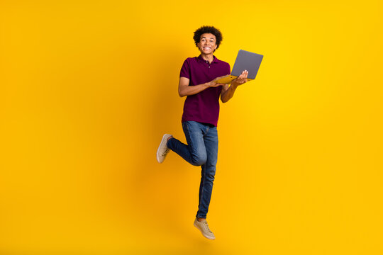 Photo of funky glad guy man wear trendy outfit jump up buy new modern device wifi connection isolated on yellow color background