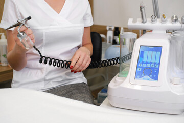 Aesthetician with Cosmetic Procedure Equipment. An esthetician is holding a professional device for...
