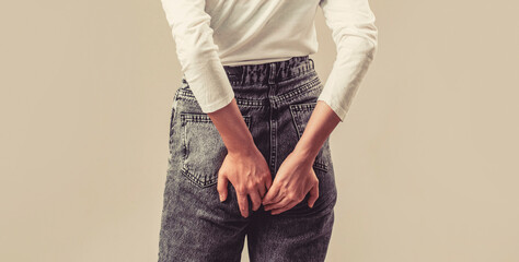 Woman suffering from hemorrhoids, anal pain on gray background