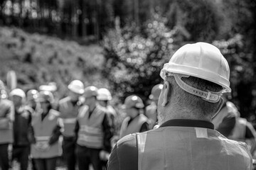Skillful worker stand together showing teamwork. Industrial people and manufacturing labor concept. Worker group wearing vest, safety. Architector, engineers on constructing site. Black and white - Powered by Adobe