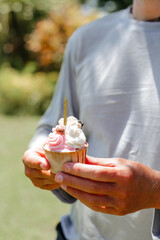 Man holding a delicious cupcake with a candle. Birthday celebration in the park