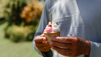 Banner man holding cupcake in his hands. Birthday celebration in the park