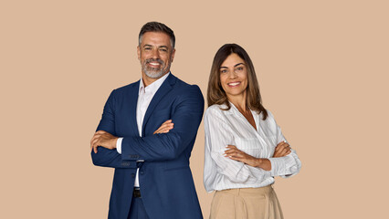Portrait of two smiling mature Latin business man, European business woman standing arms crossed...