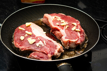 frying two sirloin steaks with garlic for dinner