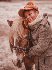 the boy hugs the pony and smiles thoughtfully