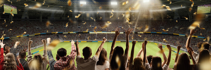 Sport match. Back view of football fans cheering favorite soccer team at crowded stadium at evening...