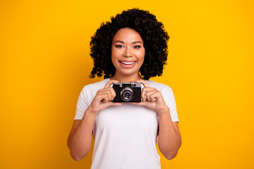 Photo of cheerful good mood woman wear white t-shirt tacking photos vintage camera isolated yellow...
