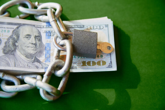 Hundred-dollar bills with a chain on them and a closed lock, blocking financial aid, blocking funds