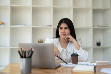 Young businesswoman stressed and having headache while working at desk with laptop in modern office