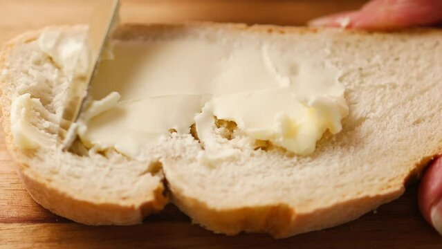 Woman spreading soft butter on slice of bread. Spreading cream cheese on bread. Housewife making sandwich for breakfast. 