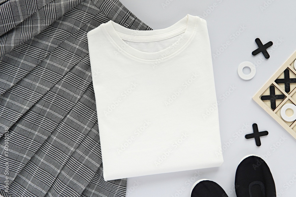 Wall mural folded white t-shirt mockup, school uniform, creative flat lay with kids clothes and table games.