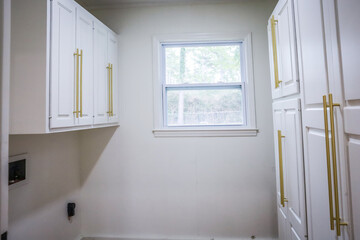 Updated white shaker cabinets with elegant gold sleek thin hardware in a newly renovated laundry...