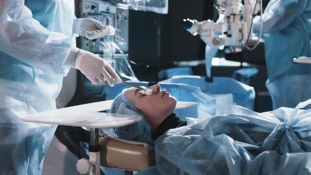 In a modern ophthalmology operating room, a patient is prepared for surgery. A group of medical workers in an ophthalmology clinic. The concept of modern technologies, vision correction and treatment.