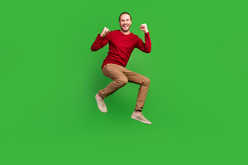 Fototapeta na wymiar Full size photo of ecstatic man dressed red pullover brown pants jumping win gambling scream yeah isolated on green color background