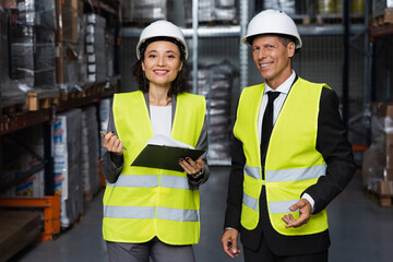 professional headshot, middle aged supervisor and female employee in hard hat with clipboard