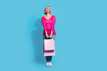 Full size photo of pretty young girl shopping bags look up empty space wear trendy pink knitted...