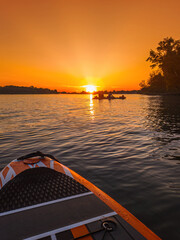 SUP board on water surface background close up. Surfing and SUP boarding equipment in sunset lights close-up.