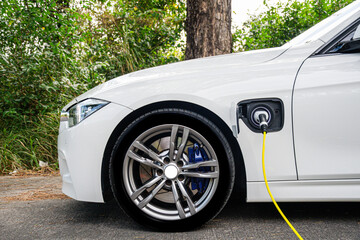 The white color electric vehicle plugged the cable for charging