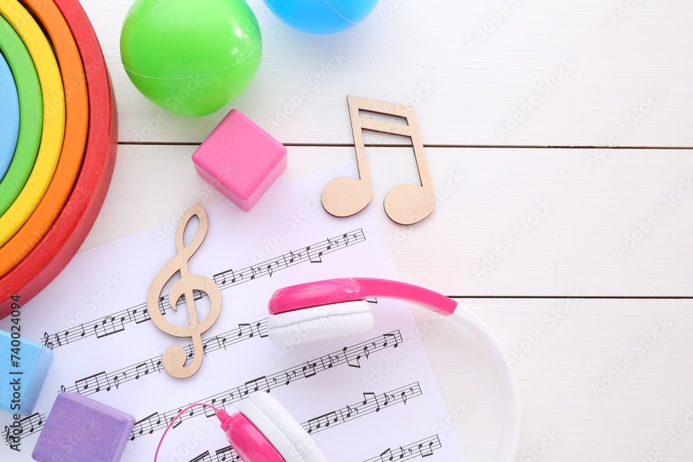 Sticker Notes, music sheet, headphones and toys on white wooden table, flat lay with space for text. Baby song concept